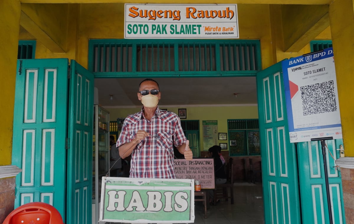 Pak Slamet di depan warung sotonya dengan plakat tulisan 'Habis'