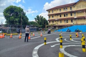 Polisi mengawasi masyarakat yang sedang melakukan ujian praktik SIM di Satpas Polresta Yogyakarta. 