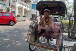 Ngatiyo, tukang becak di Jalan Margo Utomo saat diambil gambarnya, Jumat (11/8/2023). Sudah biasa ia berhari-hari ia tidak mendapatkan penumpang MOJOK.CO