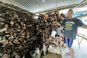 Ismarhaban, dengan kayu bakar yang digunakan untuk memasak bebek bacem di Kampung Nglengis MOJOK.CO