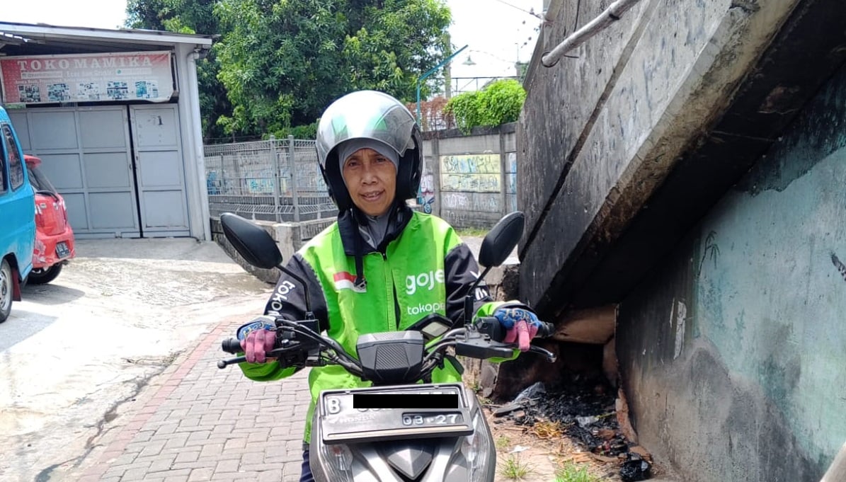 Suparti driver ojol di Jakarta mengendarai sepeda motornya untuk bekerja. MOJOK.CO