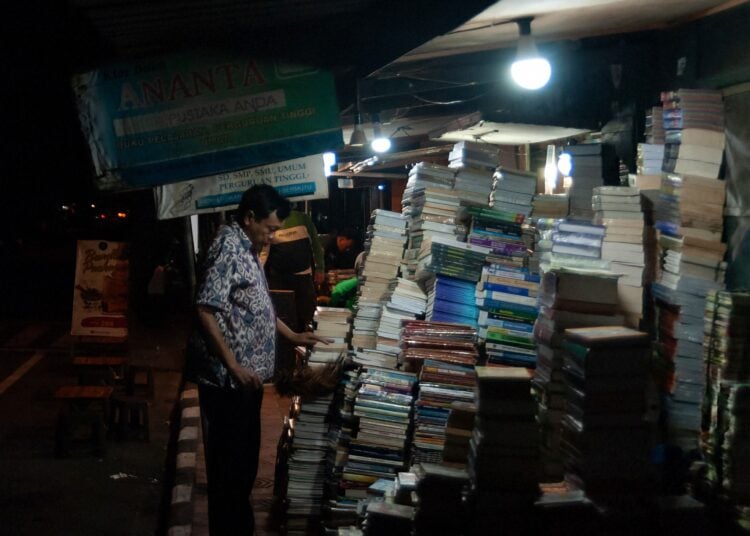 Penjual buku tampak memilah-milah bukunya MOJOK.CO