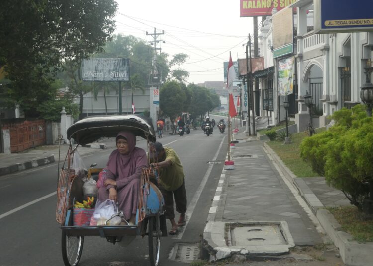Tukang becak mengantar penumpang di jalanan Kotagede, Jogja, pagi hari MOJOK.CO