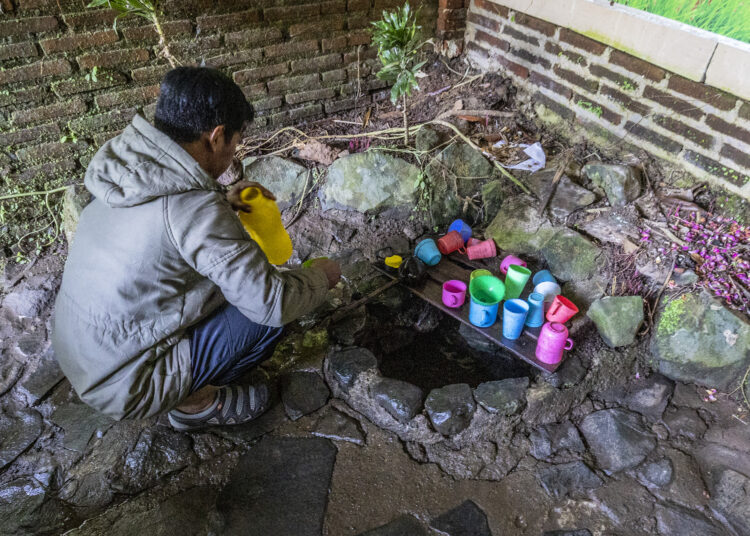 Seorang pengunjung yang hendak membawa pulang Air Tiga Rasa Rejenu, Desa Japan, Kudus MOJOK.CO