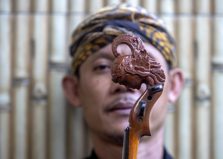 Ukiran kepala wayang di gagang biola bambu karya Mbah Min MOJOK.CO