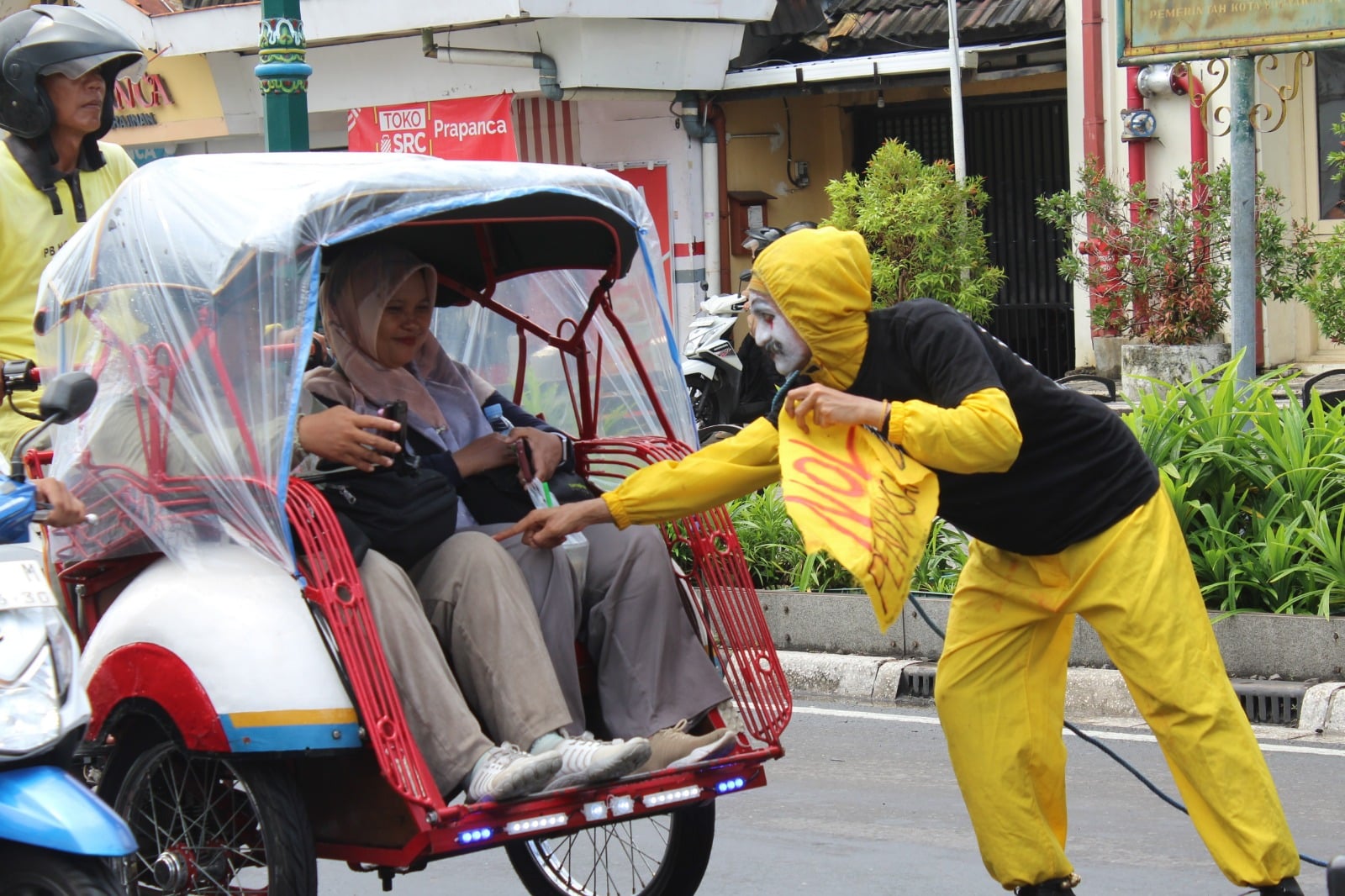 Seniman berinteraksi dengan penumpang becak. MOJOK.CO