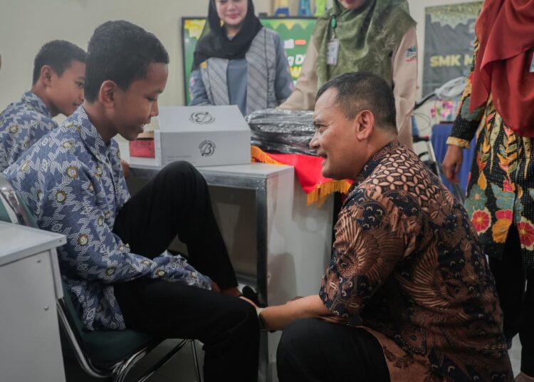 Gubernur Jawa Tengah Ahmad Luthfi pakaikan sepatu ke seorang siswa dari sekolah mitra MOJOK.CO