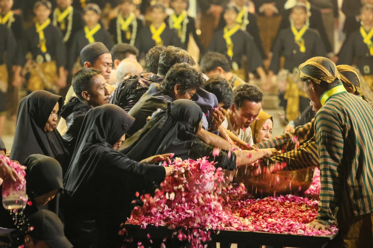 Masyarakat berebut air jamasan di malam 1 Suro di kawasan Pura Mangkunegaran Surakarta, Jawa Tengah MOJOK.CO
