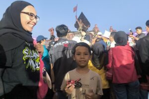 Nadim (8) bersama ibunya dan kaos yang sudah ditanda tangani pembalap idolanya, tak lupa die cast motor yang ia bawa saat bertemu Veda Ega Pratama dan Mario Aji di SO 1 Maret 1949.